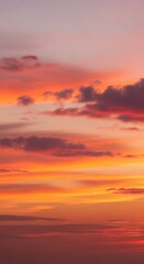 Fototapeta premium Vibrant orange and pink clouds drift across the evening sky during a beautiful sunset. Golden hour light illuminates the atmosphere, abstract, serene, evening