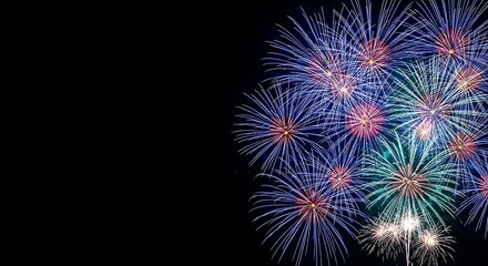 Vibrant blue and green fireworks exploding against a dark night sky with copy space on the left