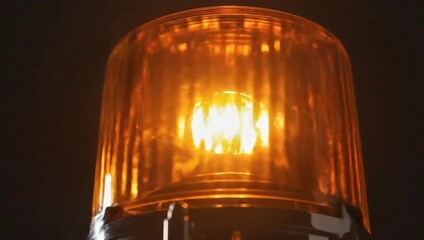 Rotating amber warning light safety beacon for emergency vehicles isolated on dark background