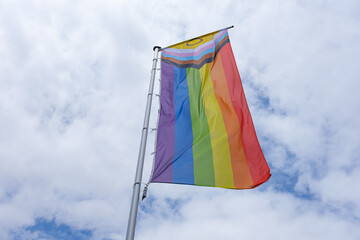 New Progress LGBTQ+ Pride Flag waving in sunlight against blue sky