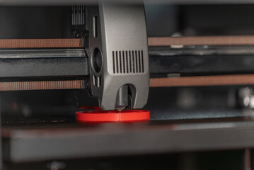 Close-up of a 3D printer extruder depositing red PLA filament to print a circular object. Ideal for technology, prototyping, and 3D printing concepts.