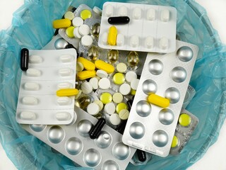 Various expired pills and expired pill blister packs are  in  a container for disposal, top view. 
