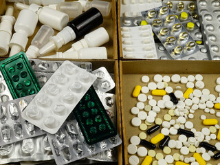 Expired medications, blisters, and used medication vials in boxes, preparing for disposal. Treatment and medicines concept
