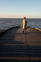 Woman contemplating sunset over sea from pier. Whitstable Kent United Kingdom