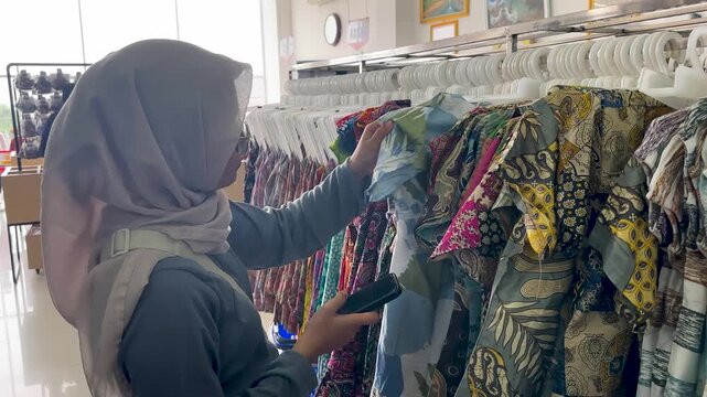 A woman selects batik fabric while shopping in a Yogyakarta store in the afternoon