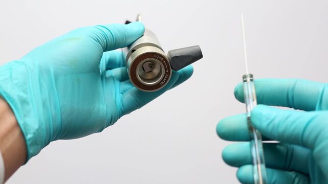 A scientist's gloved hands demonstrate loading a liquid sample into a manual HPLC injection valve using a glass microsyringe with the valve in the LOAD position.
