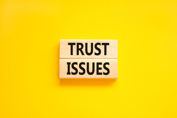 Trust issues symbol. Concept word Trust issues on beautiful wooden blocks. Beautiful yellow paper background. Business trust issues concept. Copy space.