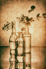 Monochrome still life with glass bottles and a bouquet of flowers