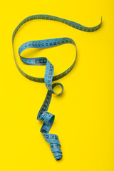 Tailor's measuring tape on yellow background