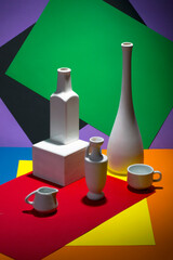 Still life with white vases on a color abstract background.