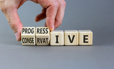 Progressive or conservative symbol. Businessman turns wooden cubes and changes word Conservative to Progressive. Beautiful grey background. Business progressive or conservative concept. Copy space.