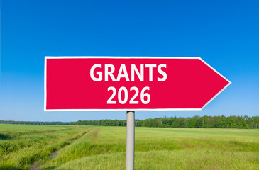 Grants 2026 symbol. Concept words Grants 2026 on beautiful red road sign. Beautiful green grass field forest and blue sky background. Business and grants 2026 concept. Copy space.
