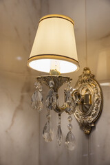 A decorative brass wall sconce featuring an ornate backplate, hanging crystal prisms