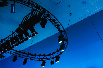 A circular truss lighting rig suspended from the ceiling casts blue tones