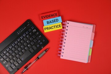 Red background with a keyboard, pink spiral notebook, and colorful wooden blocks showing 'Evidence...
