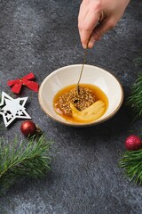 Mixing grainy and Dijon mustard with honey for a glaze on roast beef or other meats against a dark background in Christmas decor.