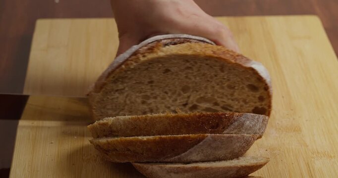 Slicing Wholegrain Bread Cri On Slice For Bruschetta. Cutting Sourdough Bread On Kitchen. Making Morning Toast Breakfast.Fresh Crisp Sourdough Bread On Table. Cutting French Multigrain Bread For Toast
