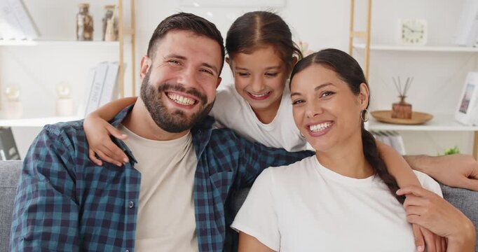Family parents daughter smiling laughing at home. On a cozy sofa, they cuddle and giggle in a living room, in casual clothes and enjoying happiness together. Concept: family love and bonding.