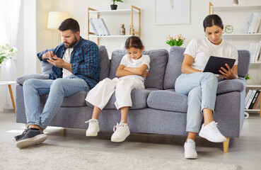 Child girl and parents on couch at home. Parents on smartphone and tablet as daughter sits upset and ignored, exposing family neglect, boredom, and disconnection. Parenthood and technology addiction.