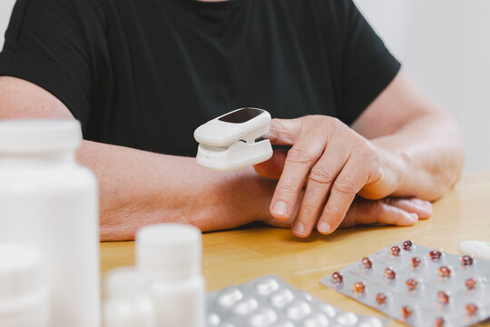 A mature woman measures her pulse with a device. - Powered by Adobe