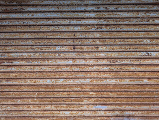 Frame texture of old rusted and peeling metal roller garage shutter door. Rust, oxidation, paint patches, distressed, textured industrial surface, decay, urban grit, deterioration, corrosion. 