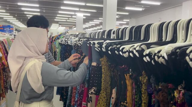  A couple examines batik cloth at a shop in Yogyakarta, exploring traditional patterns and styles