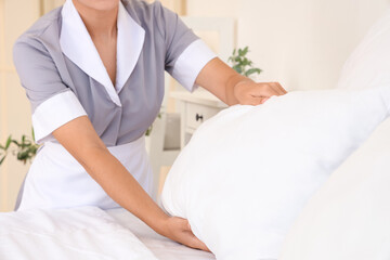 Fototapeta premium Chambermaid making bed in hotel room, closeup