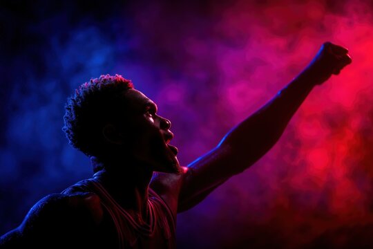 Athlete celebrating victory with raised fist in dramatic lighting during intense basketball moment