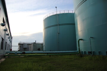Obraz premium Detailed power plant structure with chimney against the vibrant blue sky backdrop.
