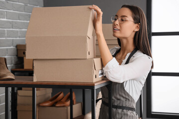 Female seller with box on shelf in warehouse store