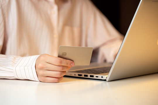 Close-up of a person holding a credit card while using a laptop, representing online shopping, digital payments, and secure internet transactions in a modern workspace