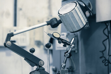 Old metrology measurement tools and lamp at the machine shop close up view desaturated image.