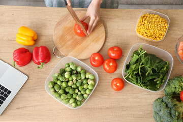 Woman cutting fresh tomatoes for freezing on wooden table