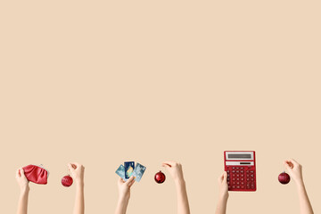 Hands holding wallet, credit cards, calculator and Christmas decorations on beige background