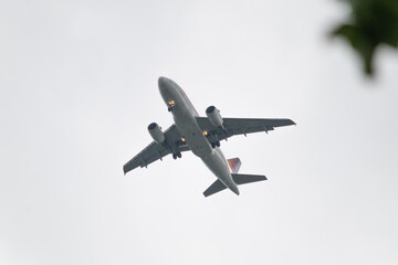 Photograph of a commercial airplane in the air against a clear sky taken from below in cloudy weather