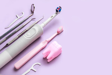 Toothbrushes, dental tools, tooth model and floss toothpicks on lilac background. World Dentist Day
