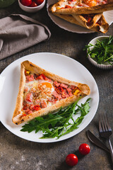 Scrambled eggs with bacon and cherry tomatoes in a tortilla and arugula on a plate vertical view