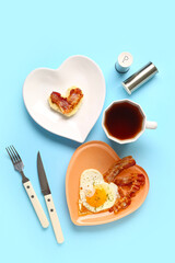 Composition with tasty bacon, fried egg, bread and cup of tea on blue background