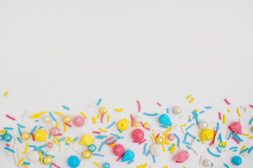 Sweet colorful sprinkles scattered on white background