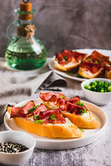 Baked sandwiches with cream cheese, prosciutto and herbs on a plate on the table vertical view