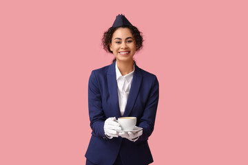Beautiful African-American stewardess with coffee on pink background