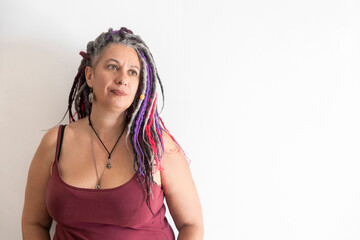 Close-up portrait of a thoughtful plus size woman with dreadlocks against a bright white background.