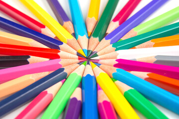 Naklejka premium Sharpened colored pencils in a starburst formation on a white backdrop, displaying a rainbow of colors. Ideal for artistic projects, school supplies, or creative design concepts.