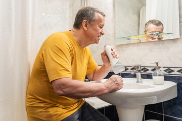 Cleaning teeth with oral irrigator after brushing, caucasian adult male performing advanced oral hygiene at bathroom sink. Man Brushing Teeth