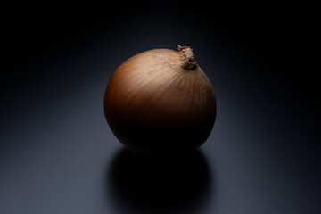 黒背景に浮かび上がる一個のタマネギを印象的に捉えた食材イメージ