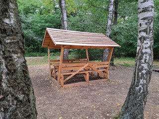 A new wooden gazebo with a table for relaxing and dining in a forest park area