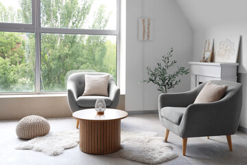 Fototapeta premium Interior of light living room with paintings, fireplace and armchairs