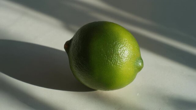A vibrant green lime dances in sunlight, its zest promises refreshing moments in a summer cocktail or a culinary creation