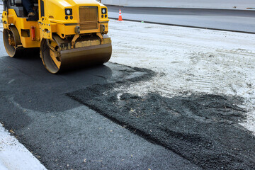 Heavy machinery is actively smoothing asphalt on city road preparing for new surface work.