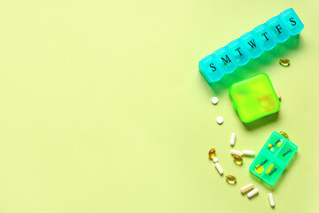 Plastic containers with pills on green background. Top view